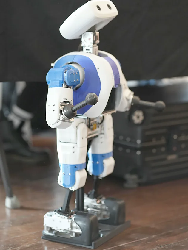 A blue and white humanoid robot on display at a PrismaX event